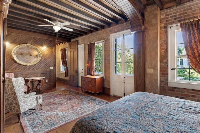 521 Dauphine St, New Orleans, LA 70112 - bedroom featuring beamed ceiling, multiple windows, brick wall, wood finished floors, and wooden walls