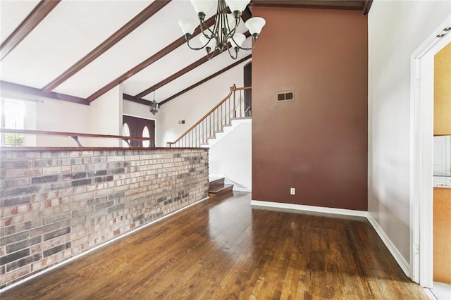 104 Magnolia Dr, Belle Chasse, LA 70037 - unfurnished living room featuring a chandelier, beam ceiling, wood finished floors, brick wall, and stairs