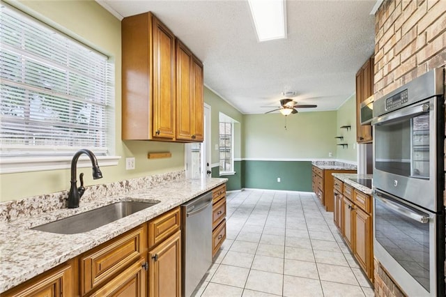 104 Magnolia Dr, Belle Chasse, LA 70037 - kitchen featuring appliances with stainless steel finishes, a textured ceiling, brown cabinetry, light stone countertops, and ceiling fan