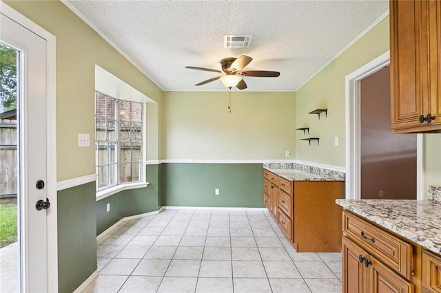 104 Magnolia Dr, Belle Chasse, LA 70037 - kitchen featuring a textured ceiling, brown cabinets, ceiling fan, ornamental molding, and light stone countertops