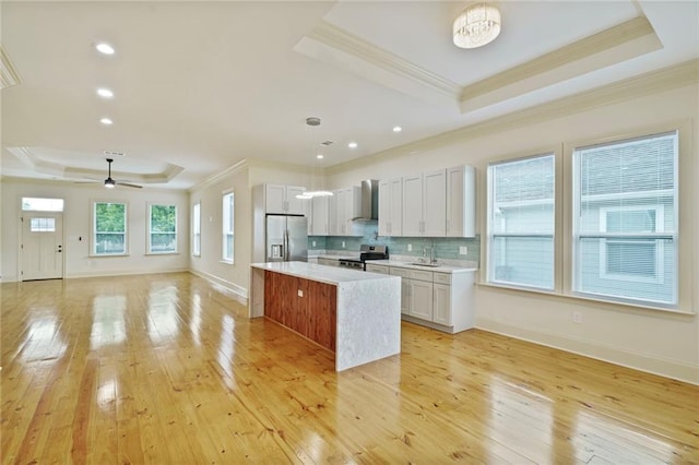 6032 Wingate Dr, New Orleans, LA 70122 - kitchen featuring a tray ceiling, stainless steel appliances, wall chimney exhaust hood, crown molding, and open floor plan