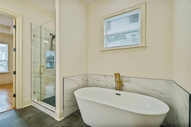 6032 Wingate Dr, New Orleans, LA 70122 - full bathroom featuring tile walls, plenty of natural light, a soaking tub, a marble finish shower, and wainscoting