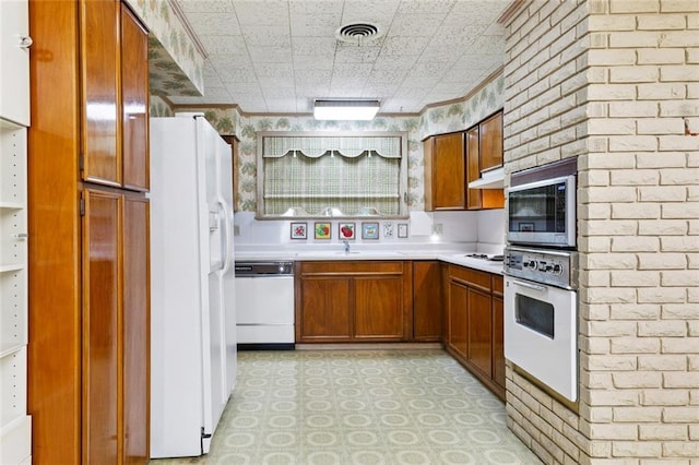 953 Homestead Ave, Metairie, LA 70005 - kitchen with white appliances, light flooring, light countertops, brown cabinetry, and under cabinet range hood
