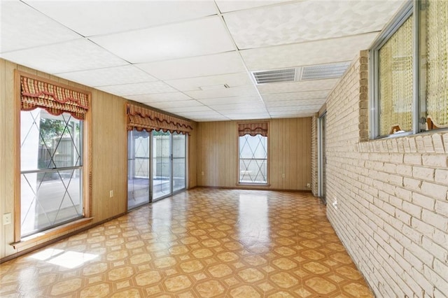 953 Homestead Ave, Metairie, LA 70005 - unfurnished room with a paneled ceiling, light floors, brick wall, and wood walls