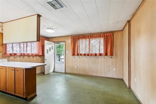 953 Homestead Ave, Metairie, LA 70005 - kitchen featuring wood walls, light countertops, brown cabinetry, and a peninsula