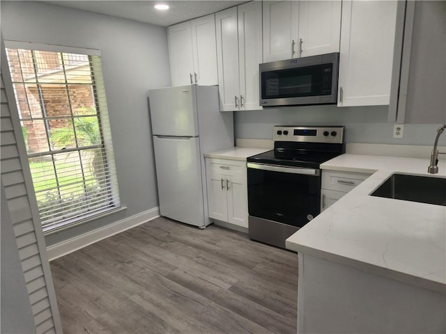 3320 N Arnoult Rd Unit 109, Metairie, LA 70002 - kitchen with appliances with stainless steel finishes, light wood-type flooring, light stone countertops, white cabinets, and recessed lighting