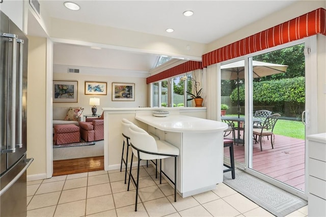 2310 Metairie Ct, Metairie, LA 70001 - kitchen with freestanding refrigerator, a breakfast bar area, light countertops, light tile patterned floors, and recessed lighting