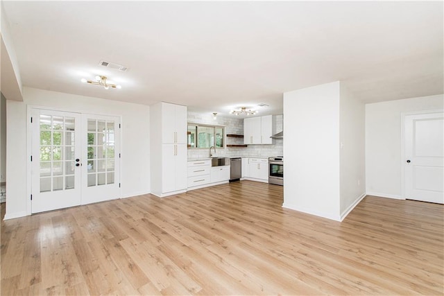 106 Woodlawn Ln, Mandeville, LA 70471 - unfurnished living room with french doors and light wood-style flooring