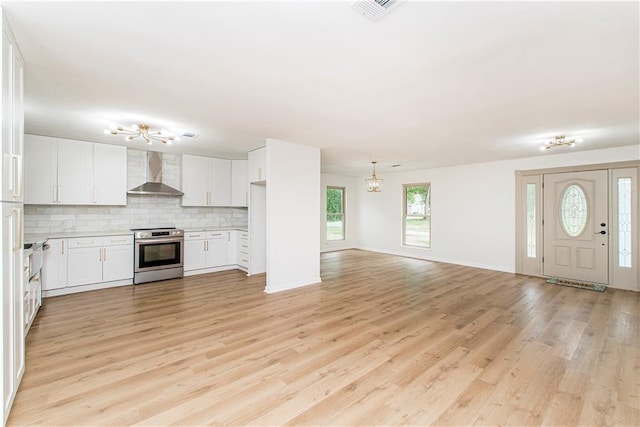 106 Woodlawn Ln, Mandeville, LA 70471 - kitchen with electric stove, wall chimney exhaust hood, open floor plan, a chandelier, and backsplash