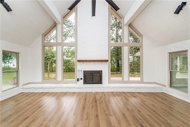106 Woodlawn Ln, Mandeville, LA 70471 - unfurnished living room featuring high vaulted ceiling, beamed ceiling, plenty of natural light, a brick fireplace, and wood finished floors