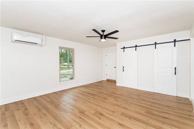 106 Woodlawn Ln, Mandeville, LA 70471 - unfurnished bedroom featuring a wall mounted air conditioner, a barn door, light wood finished floors, and a ceiling fan