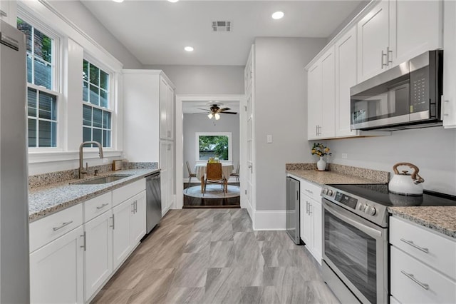 2625 Ursulines Ave, New Orleans, LA 70119 - kitchen featuring stainless steel appliances, white cabinetry, light stone countertops, and recessed lighting