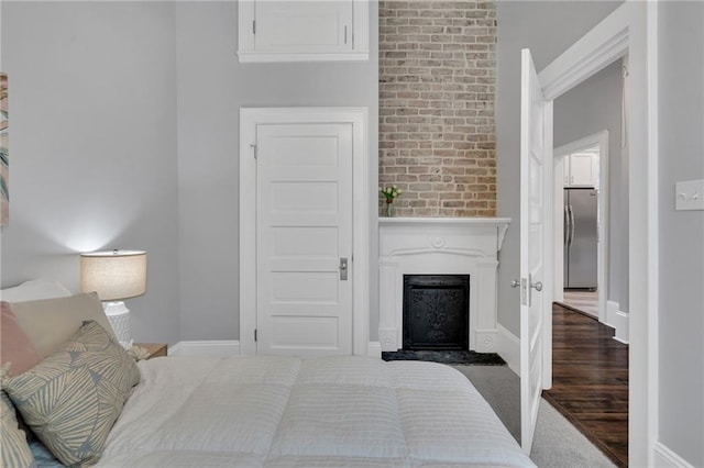 2625 Ursulines Ave, New Orleans, LA 70119 - bedroom with freestanding refrigerator, a fireplace with raised hearth, and brick wall