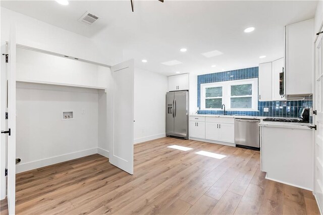 566 Gelpi Ave, Jefferson, LA 70121 - kitchen featuring stainless steel appliances, white cabinets, light wood-style flooring, backsplash, and light countertops
