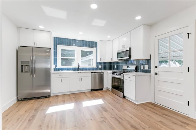 566 Gelpi Ave, Jefferson, LA 70121 - kitchen with stainless steel appliances, backsplash, light countertops, white cabinets, and light wood-style floors