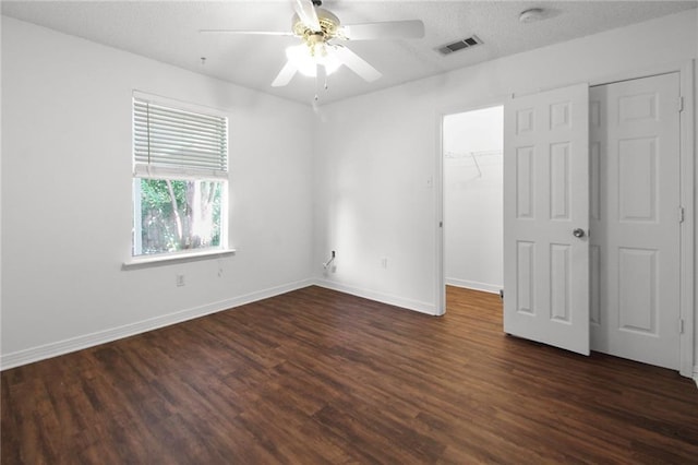 345 Sugarpine Dr, Gretna, LA 70056 - unfurnished bedroom with dark wood-style flooring, a walk in closet, a closet, a ceiling fan, and a textured ceiling