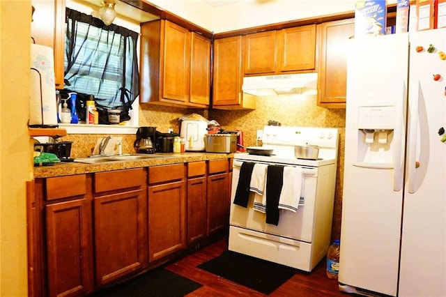 110 E Green St, Hammond, LA 70403 - kitchen with white appliances, under cabinet range hood, dark wood-type flooring, backsplash, and brown cabinets