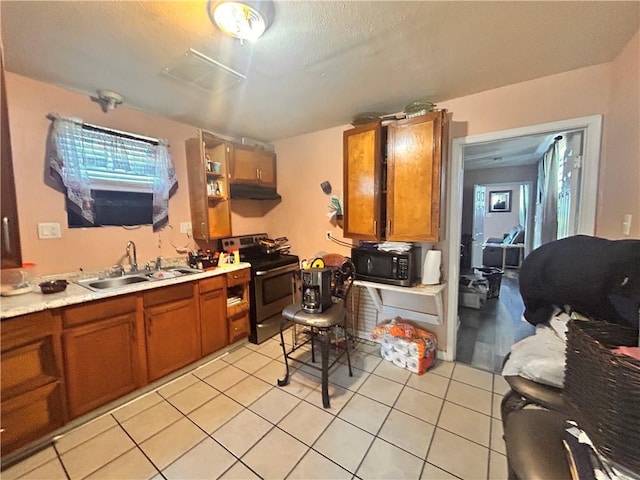 4040 Velie St, New Orleans, LA 70126 - kitchen with stainless steel range with electric stovetop, black microwave, brown cabinets, under cabinet range hood, and light tile patterned floors