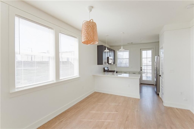 414345 Ulloa St, New Orleans, LA 70119 - kitchen with stainless steel appliances, light countertops, light wood-style floors, a peninsula, and hanging light fixtures