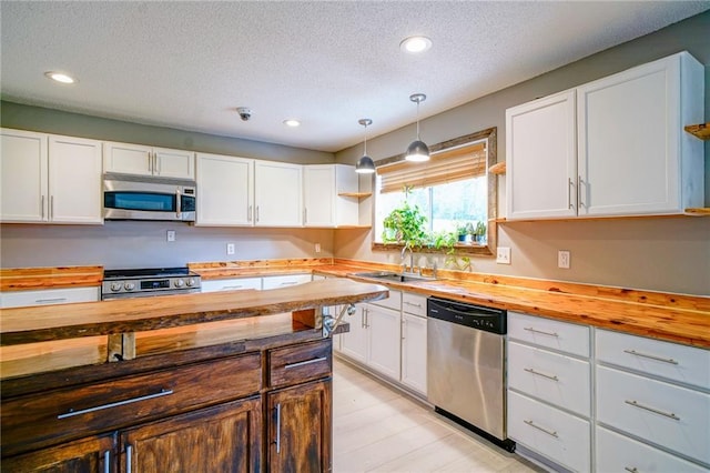 808 N Pearl St, Slidell, LA 70461 - kitchen with butcher block counters, stainless steel appliances, a textured ceiling, white cabinets, and recessed lighting