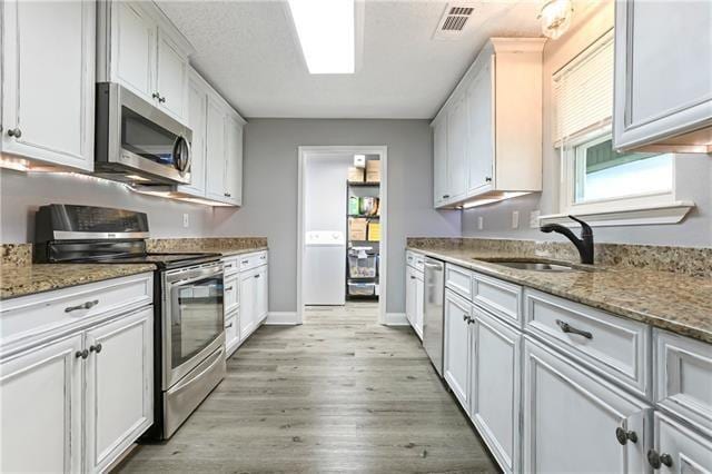 5080 Betty Mae St, Lafitte, LA 70067 - kitchen with stainless steel appliances, light wood-style floors, white cabinets, and light stone counters