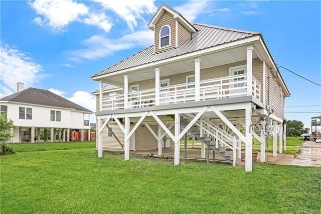 5080 Betty Mae St, Lafitte, LA 70067 - back of property with a lawn and a metal roof
