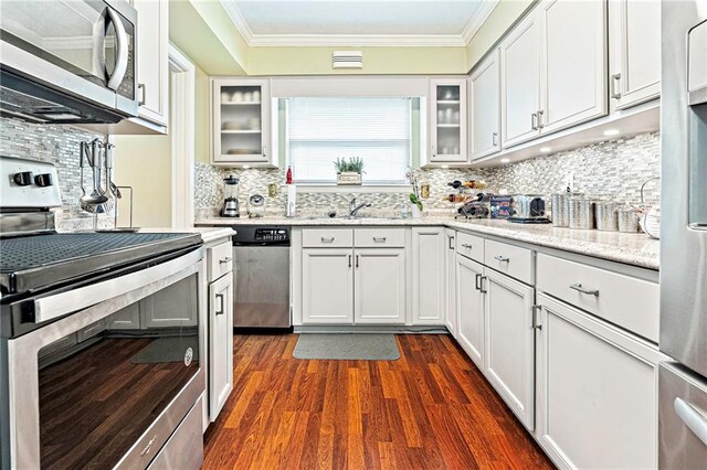 2018 Saint Nick Dr, New Orleans, LA 70131 - kitchen with appliances with stainless steel finishes, dark wood-style flooring, ornamental molding, white cabinets, and decorative backsplash