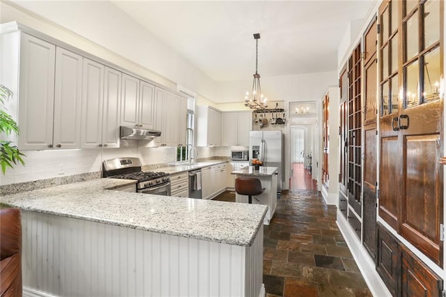 401 Pelican Ave, New Orleans, LA 70114 - kitchen featuring appliances with stainless steel finishes, stone tile flooring, a center island, a chandelier, and light stone counters