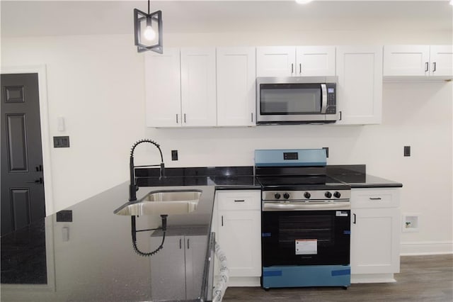 4235 Alfred St, New Orleans, LA 70122 - kitchen featuring stainless steel appliances, white cabinetry, dark wood-style flooring, dark stone countertops, and decorative light fixtures