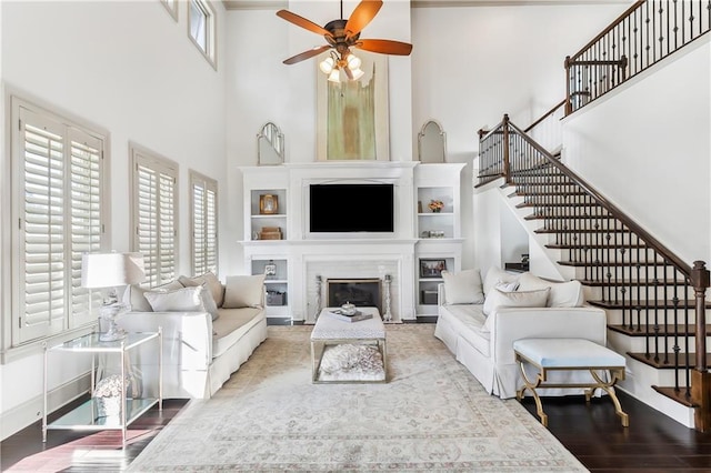 1456 Cherokee Ave, Metairie, LA 70005 - living area with a towering ceiling, stairway, a glass covered fireplace, a ceiling fan, and wood finished floors