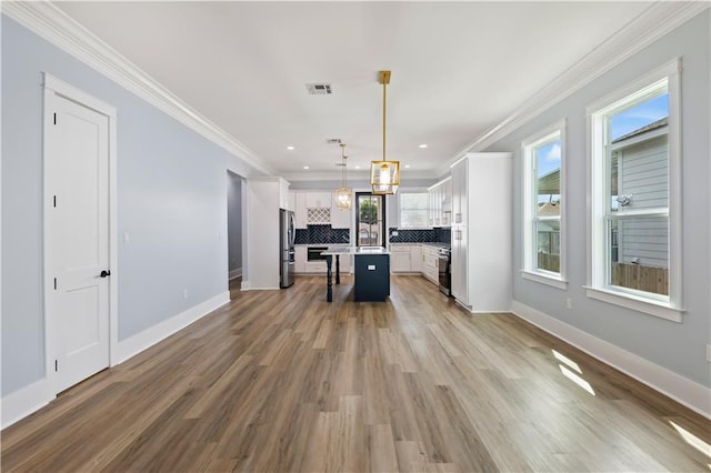 1316 Hickory Ave, Harahan, LA 70123 - kitchen featuring freestanding refrigerator, tasteful backsplash, ornamental molding, white cabinetry, and a breakfast bar