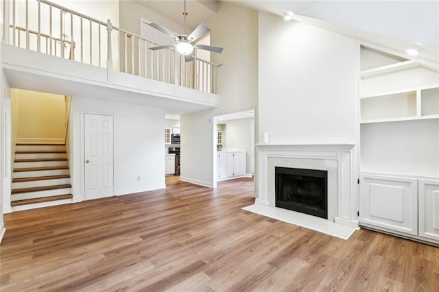 3523 Audubon Trce Unit 3523, Jefferson, LA 70121 - unfurnished living room with high vaulted ceiling, ceiling fan, stairs, a fireplace, and wood finished floors