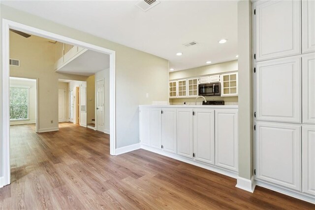 3523 Audubon Trce Unit 3523, Jefferson, LA 70121 - kitchen featuring stainless steel microwave, light wood-style floors, white cabinets, glass insert cabinets, and recessed lighting