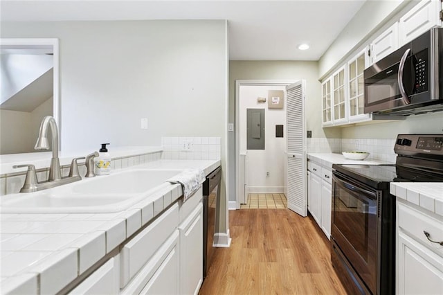 3523 Audubon Trce Unit 3523, Jefferson, LA 70121 - kitchen with stainless steel appliances, tile counters, white cabinets, light wood-style floors, and glass insert cabinets