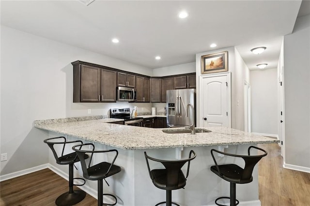 41763 Whisper Woods Rd, Ponchatoula, LA 70454 - kitchen with stainless steel appliances, wood finished floors, dark brown cabinetry, light stone countertops, and recessed lighting
