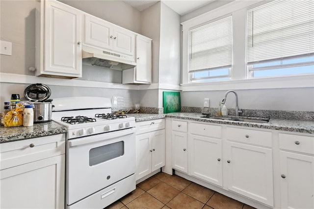 1631 S Salcedo St, New Orleans, LA 70125 - kitchen featuring white range with gas cooktop, under cabinet range hood, white cabinetry, light tile patterned floors, and light stone countertops