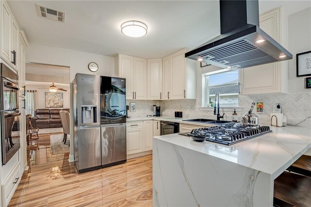 42 Melrose Dr, Destrehan, LA 70047 - kitchen featuring appliances with stainless steel finishes, wall chimney exhaust hood, a peninsula, and tasteful backsplash