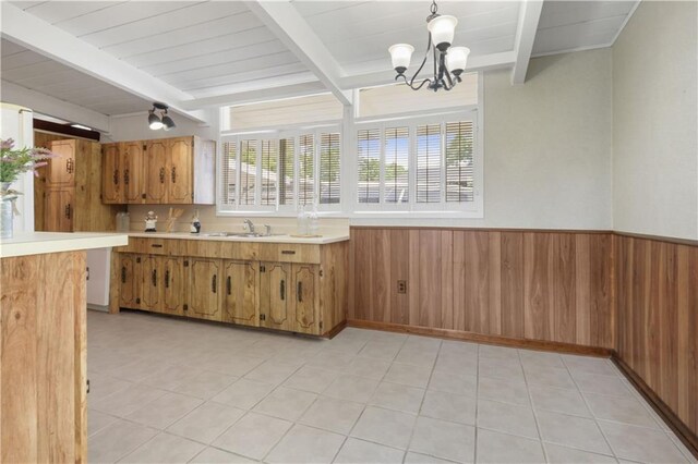 2812 Green Acres Rd, Metairie, LA 70003 - kitchen with beamed ceiling, light countertops, a chandelier, wainscoting, and brown cabinetry