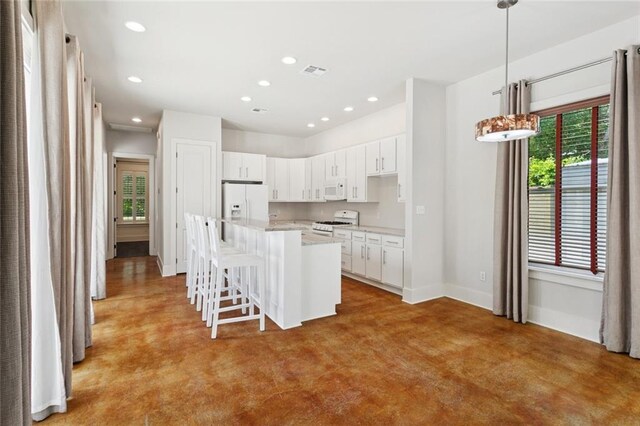 904 W 16th Ave, Covington, LA 70433 - kitchen featuring white appliances, a center island, a kitchen bar, recessed lighting, and white cabinets