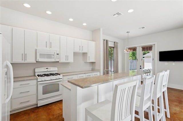 904 W 16th Ave, Covington, LA 70433 - kitchen featuring white appliances, french doors, recessed lighting, a kitchen breakfast bar, and white cabinets