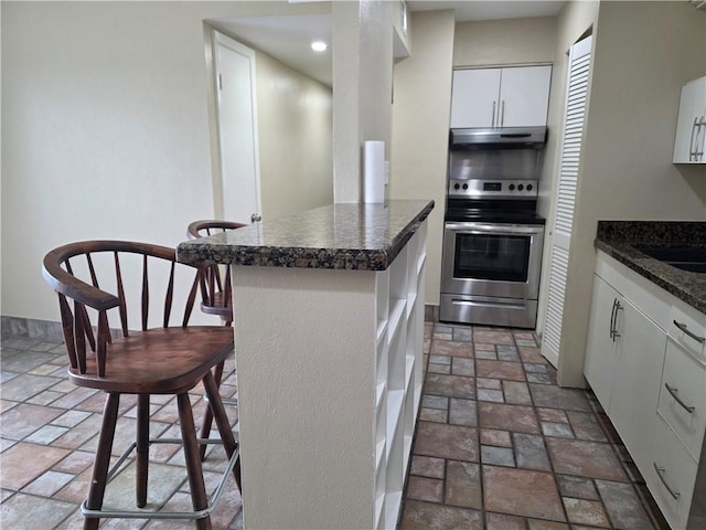 4829 Wabash St Unit 307, Metairie, LA 70001 - kitchen with electric range, under cabinet range hood, stone tile flooring, white cabinets, and recessed lighting