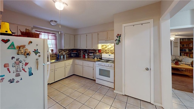 3229 Hero Dr, Gretna, LA 70053 - kitchen featuring white appliances, under cabinet range hood, light tile patterned flooring, decorative backsplash, and white cabinets