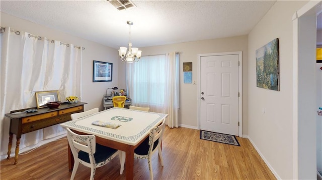3229 Hero Dr, Gretna, LA 70053 - dining area featuring light wood-style flooring, a chandelier, and a textured ceiling