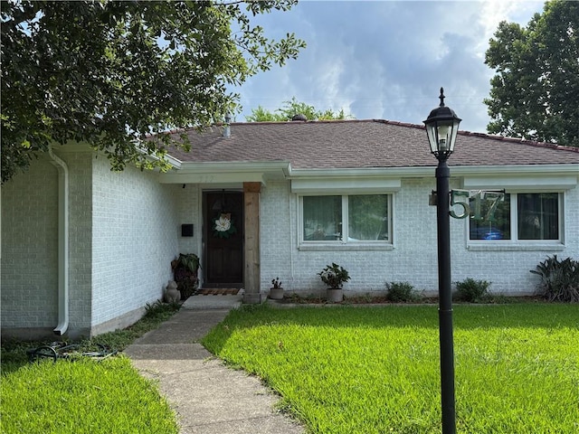 517 Colony Pl, Metairie, LA 70003 - view of front facade with a front yard, brick siding, and roof with shingles