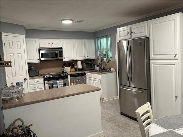 517 Colony Pl, Metairie, LA 70003 - kitchen with appliances with stainless steel finishes, ornamental molding, white cabinets, and a peninsula