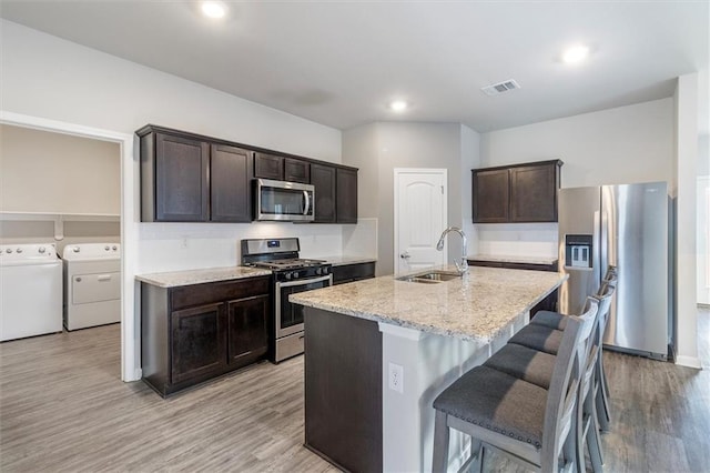 7542 1ST Lake Dr, Slidell, LA 70461 - kitchen featuring stainless steel appliances, washing machine and dryer, dark brown cabinetry, light wood-type flooring, and recessed lighting