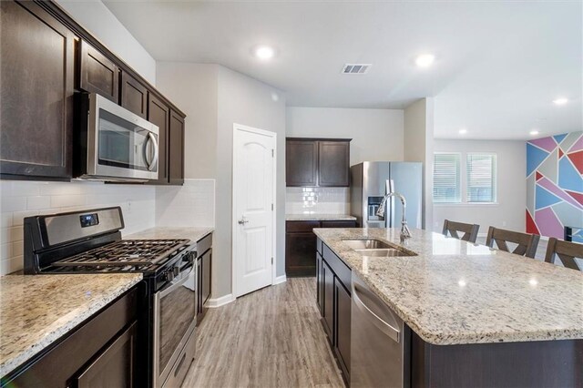 7542 1ST Lake Dr, Slidell, LA 70461 - kitchen featuring stainless steel appliances, a kitchen island with sink, dark brown cabinets, light stone countertops, and recessed lighting