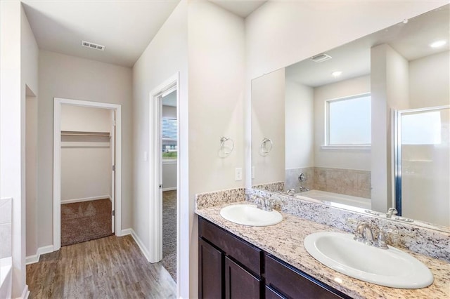 7542 1ST Lake Dr, Slidell, LA 70461 - bathroom featuring a spacious closet, double vanity, a garden tub, and wood finished floors