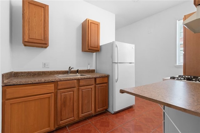 2446 N Rocheblave St, New Orleans, LA 70117 - kitchen with wall chimney range hood, freestanding refrigerator, dark countertops, and brown cabinets
