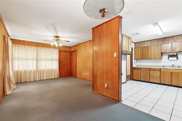 508 Arnold Ave, River Ridge, LA 70123 - kitchen with a ceiling fan, brown cabinets, light countertops, wood walls, and light colored carpet